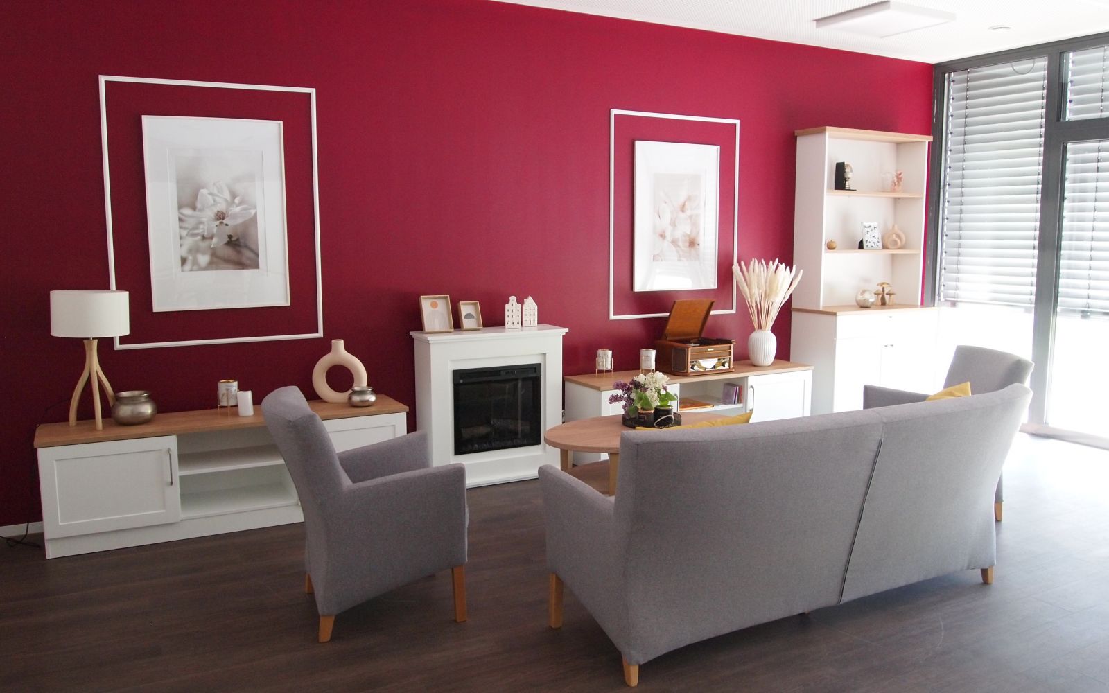 Graues Sofa und Sessel vor pinker Wand und weißen, modernen Möbeln und Bildern.